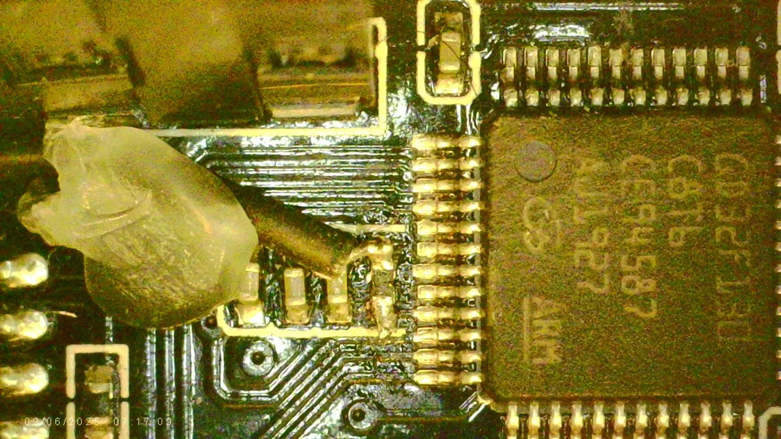 Microscope view of a fine bodge wire tacked to the reset pin (pin 7) on the top of the component and held with hot glue